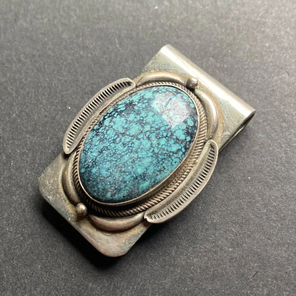 Silver toned money clip with polished blue stone. No stamps.